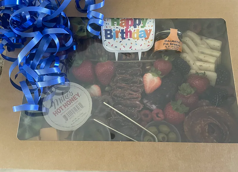 Windowed charcuterie gift box with a Happy Birthday topper and blue ribbon, ready for delivery