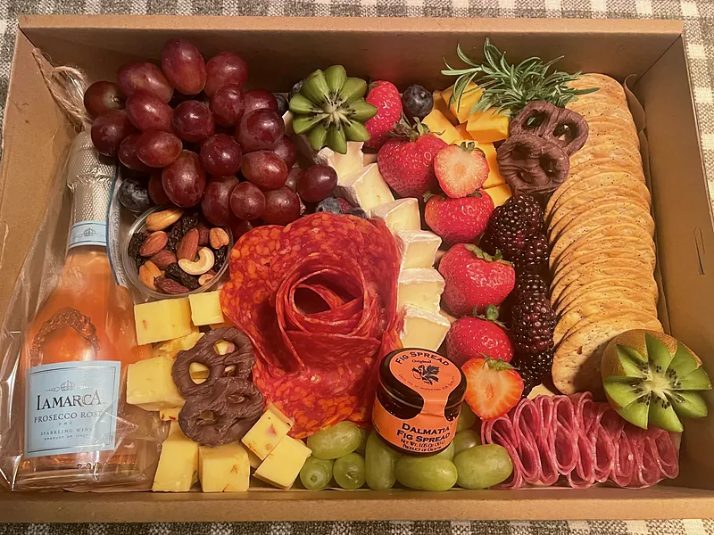 Charcuterie gift box with a pepperoni rose, brie, cheddar, strawberries, blackberries, grapes, chocolate pretzels and fig spread