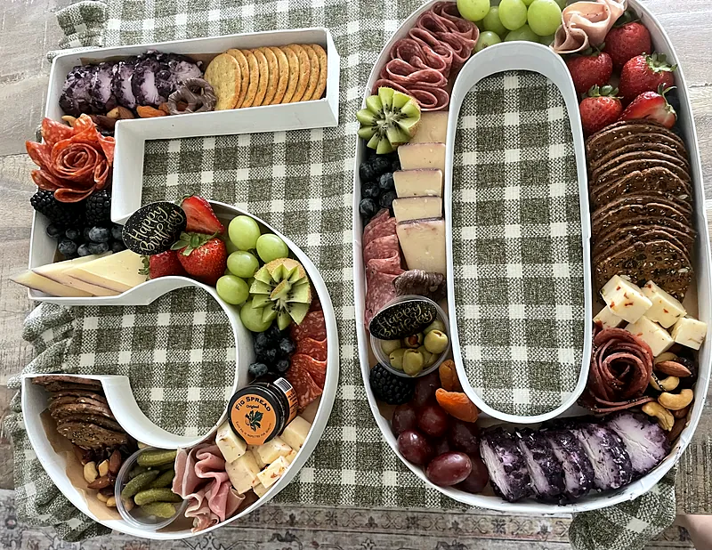 Number 50 charcuterie board for a 50th birthday filled with salami roses, cheeses, fruit, crackers and Happy Birthday toppers